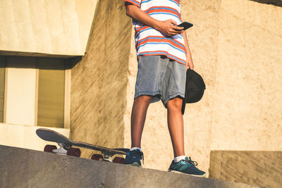 Boy using smartphone app with concrete background outdoor in urban context. young male having fun