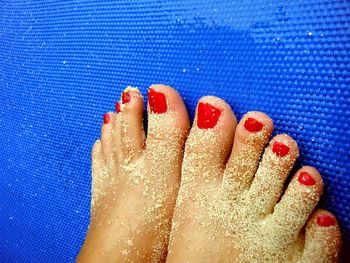 Low section of woman with sand on feet over blue mat