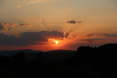 Scenic view of silhouette mountains against orange sky