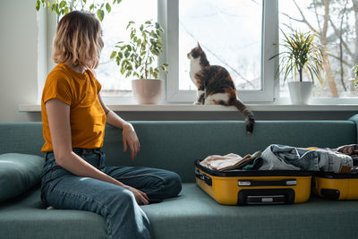 Side view of woman sitting on sofa at home