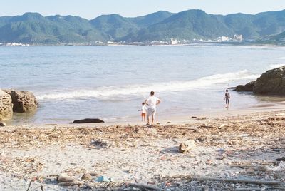 Rear view of people standing on beach