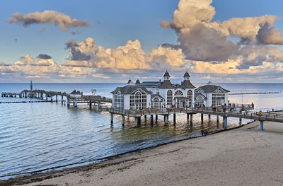 Pier on beach by sea against sky