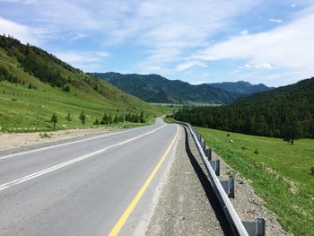 Road amidst green landscape against sky