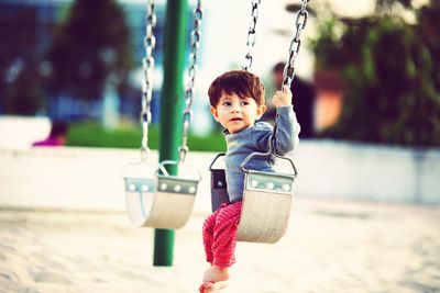 Boy sitting on swing at playground