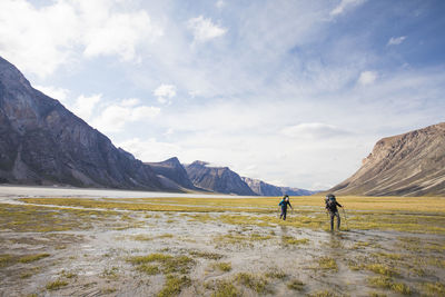 Two backpackers cross wet swamp land in akshayak pass.