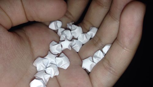 Cropped hands holding beads against black background