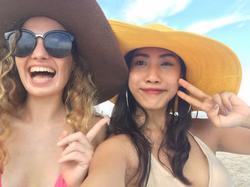 Portrait of happy friends gesturing at beach