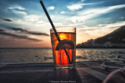 Glass of water on table against sky during sunset