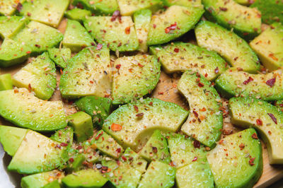 Close-up of sliced avocado pieces on a wooden cutting board. avocado covered with spices and salt in