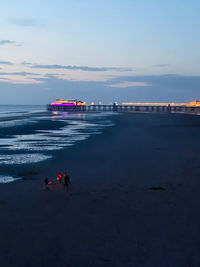 People on beach against sky during sunset