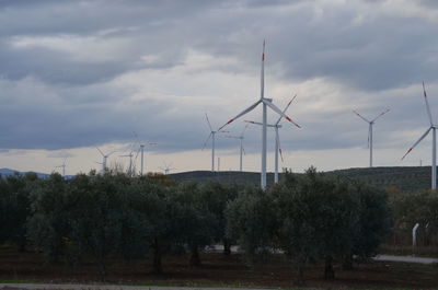 Wind turbines on field against sky