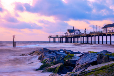 Long exposure, sunrise at southwold pier with stone groynes and a moody sky in england 