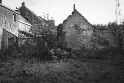 Old abandoned house by building against sky