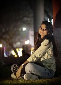 Side view of young woman sitting at night