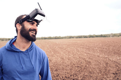 Man smiles in the field with his 3d glasses after blowing up his drone
