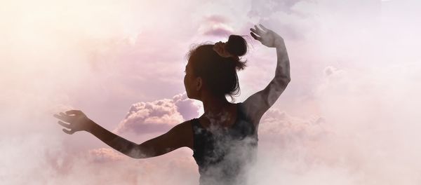 Double exposure of dancing woman and cloudy sky during sunset