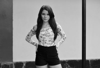 Portrait of beautiful young woman standing against wall