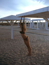 Woman in bikini at beach against sky