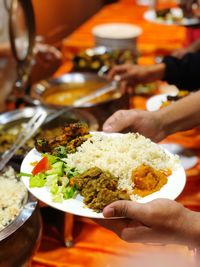 Cropped hands of people holding plates at buffet