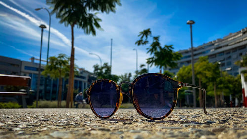 Close-up of sunglasses on street against sky