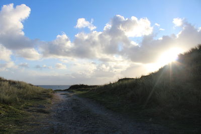 Road amidst field against sky