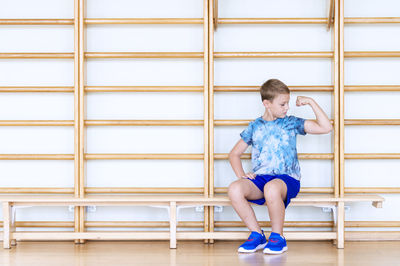 Full length of boy sitting against wall