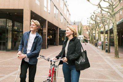 Smiling young couple traveling with skateboard and bicycle in city