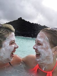 Cheerful women with mud mask in blue lagoon