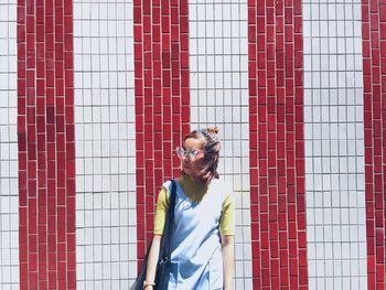 Young woman standing by striped tiled wall