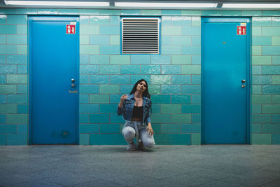 Full length of woman sitting against building