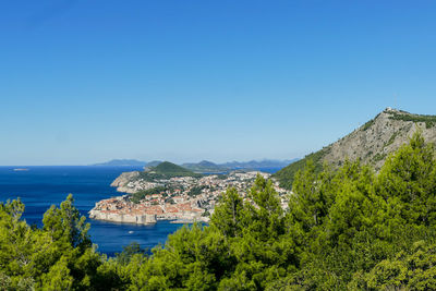 Scenic view of sea and mountains against clear blue sky