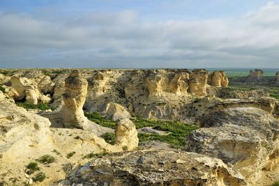 Rock formations on landscape against cloudy sky