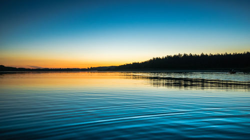 Scenic view of lake against clear sky at sunset