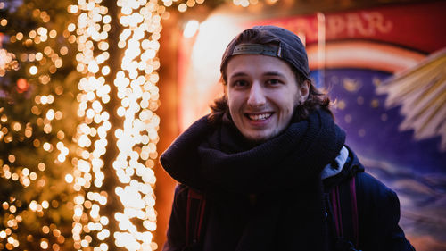 Close-up portrait of smiling man in illuminated city during winter