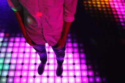 Low section of man standing on illuminated dance floor