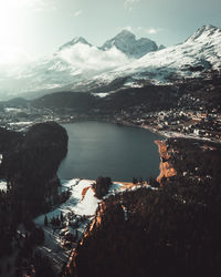 Aerial view of lake by snowcapped mountains against sky