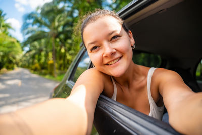 Portrait of smiling young woman sitting in car