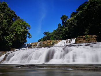 Scenic view of waterfall in forest against sky
