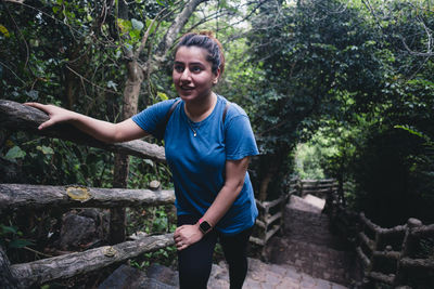 Full length of happy young woman standing in forest