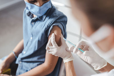 Nurse vaccinating boy with face mask at healthcare center