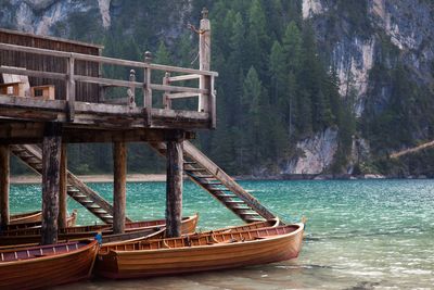 Boats moored below stilt house in lake against mountains