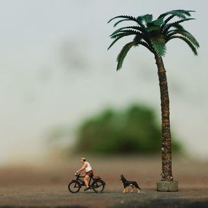 Figurine riding bicycle against sky