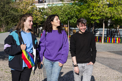 Young diverse friends walking on the street with the lgbt rainbow flag.