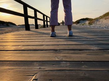 Low section of man standing on pier at beach