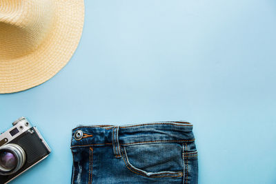 Directly above shot jeans with sun hat and camera on table