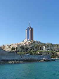 View of buildings by sea against clear sky