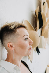 Hipster modern woman and many straw hats like interior decorate the walls in apartment