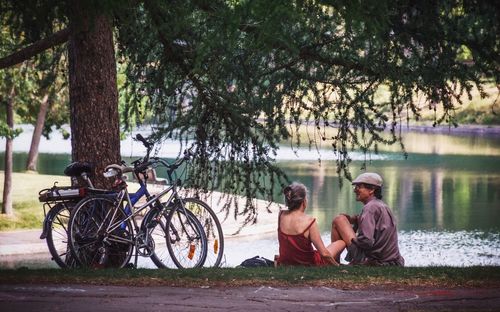 Men sitting on bicycle by tree