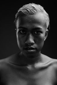 Close-up portrait of shirtless man against black background