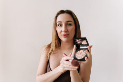 A beautiful natural woman makeup artist preens herself with makeup on a white isolated background